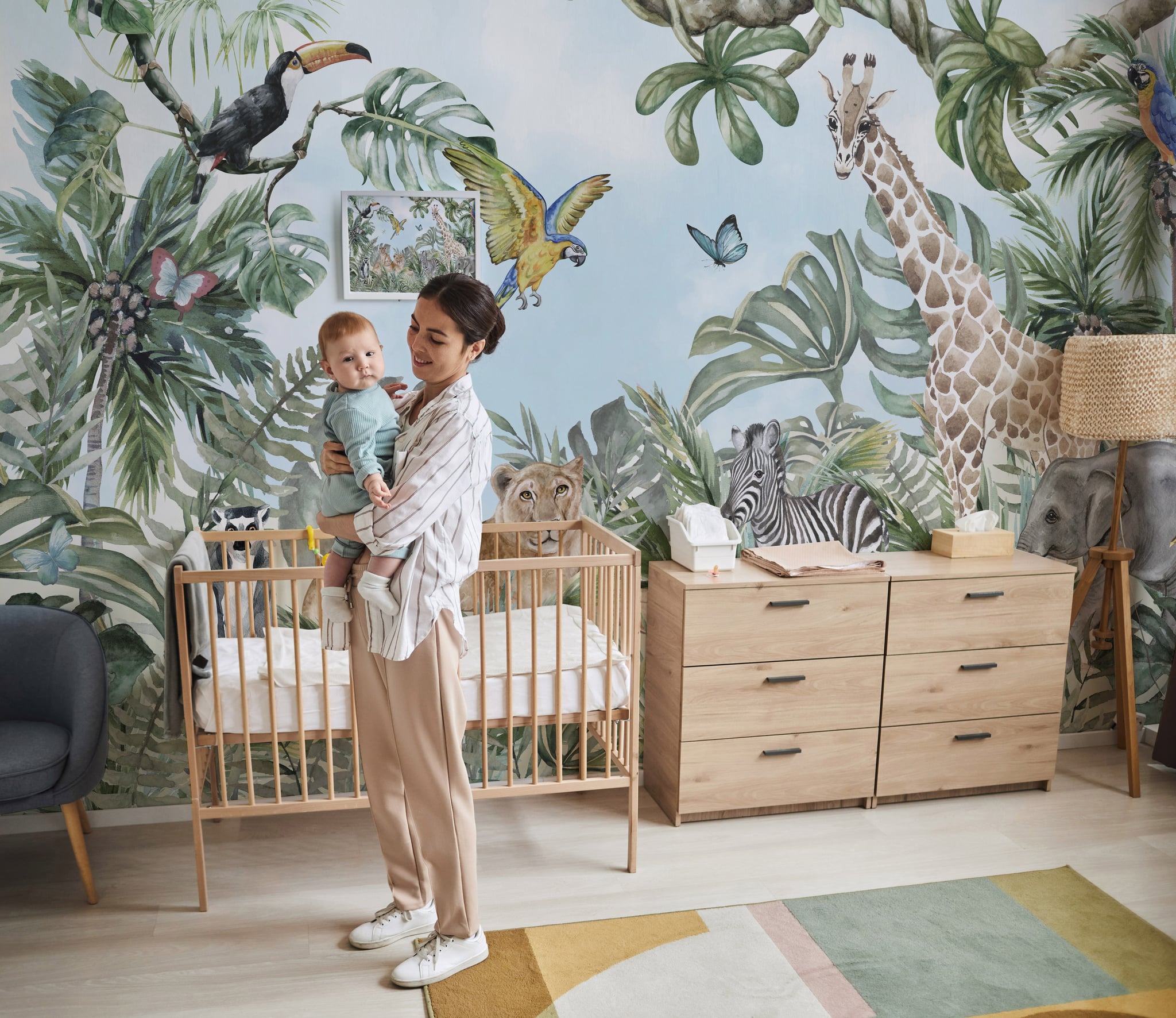 : Watercolor safari nursery wallpaper with giraffe, zebra, elephant and tropical leaves on a soft blue background